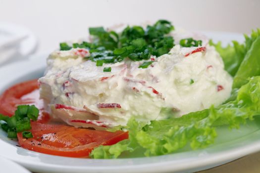 Close-up picture of a radish salad with lettuce, tomato, parsley and mayonnaise on the plate.