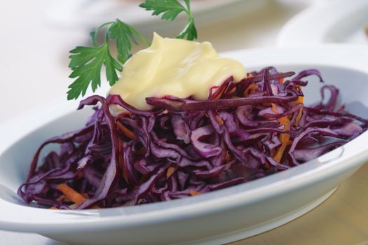Close-up picture of a salad from red cabbage with mayonnaise and parsley.