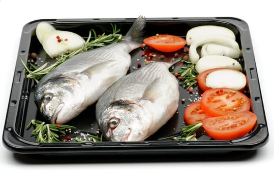 Preparing to FryingTwo Fresh Gilthead Fish with Onion, Tomatoes, Spices and Rosemary on Black Dripping Pan on white background