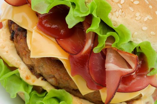 Tasty Hamburger with Beef, Bacon, Cheese, Tomato, Lettuce,  Cheese Sauce and Ketchup on Sesame Seed Bun closeup