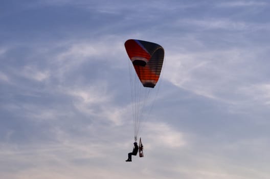 Photo shows a paraglider flies on a background of blue sky.