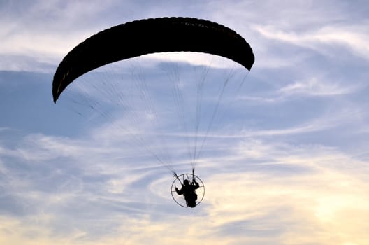 Photo shows a paraglider flies on a background of blue sky.