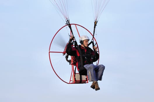 Photo shows a paraglider flies on a background of blue sky.