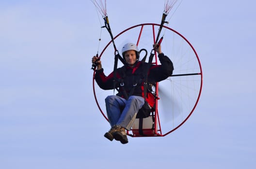 Photo shows a paraglider flies on a background of blue sky.