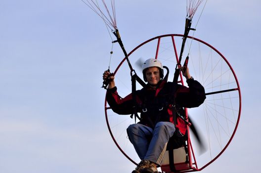 Photo shows a paraglider flies on a background of blue sky.