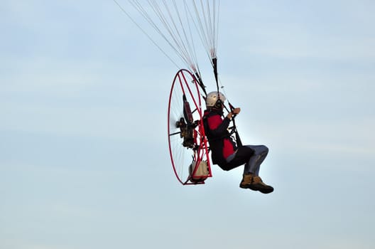 Photo shows a paraglider flies on a background of blue sky.