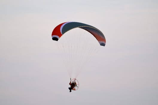 Photo shows a paraglider flies on a background of blue sky.