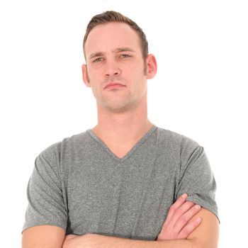 Unimpressed young man with a serious expression standing with his arms folded looking at the camera isolated on white