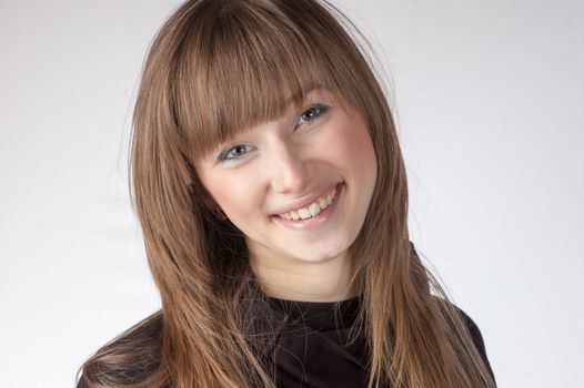 Head and shoulder portrait of smiling girl with blond hair isolated on white background.