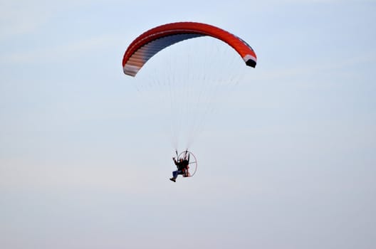 Photo shows a paraglider flies on a background of blue sky.