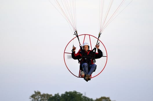 Photo shows a paraglider flies on a background of blue sky.