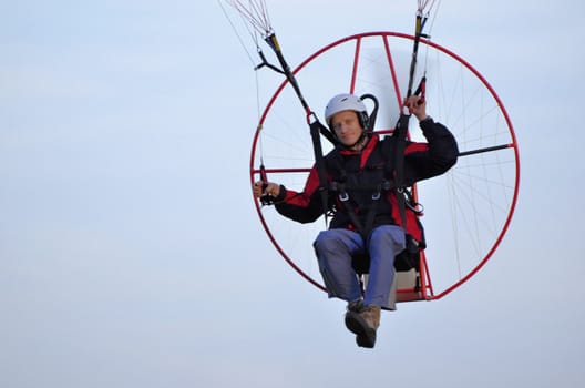 Photo shows a paraglider flies on a background of blue sky.