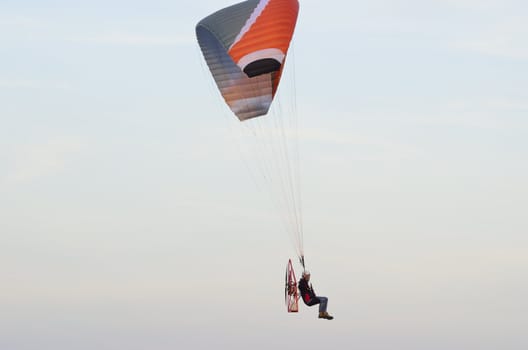 Photo shows a paraglider flies on a background of blue sky.