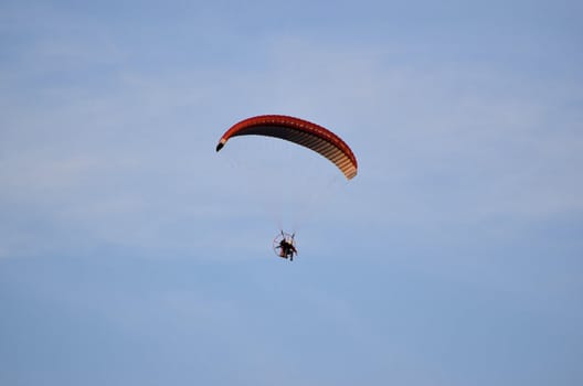 Photo shows a paraglider flies on a background of blue sky.