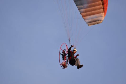 Photo shows a paraglider flies on a background of blue sky.