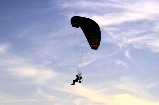 Photo shows a paraglider flies on a background of blue sky.