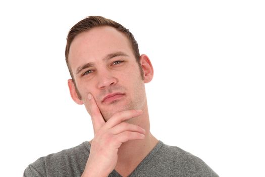 Pensive attractive young man standing thinking with his hand to his chin and a faraway look in his eyes isolated on white