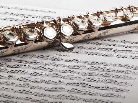 A used flute rests across an open etude musical score       