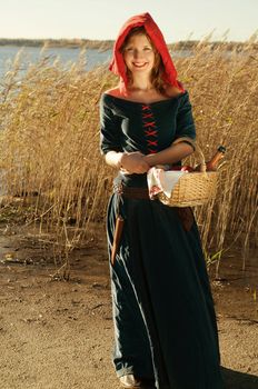 red Riding  hood standing beside lake . beautiful girl in medieval dress