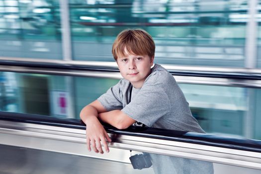boy in the departure hall  in the new Airport Suvarnabhumi in Bangkok on a moving staircase