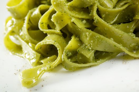 Tagliatelle pasta with pesto on light plate. closeup