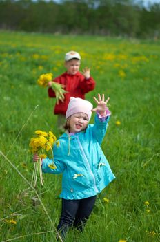 boy and small girl  on meadow with dandelion