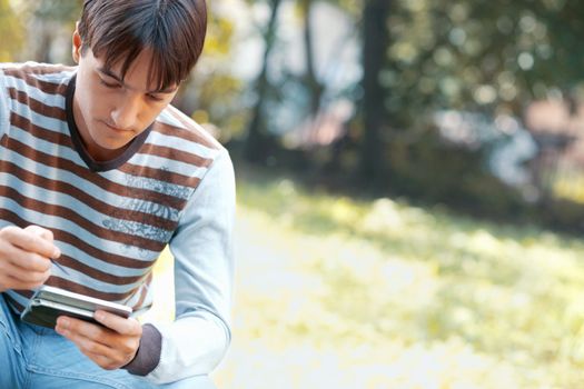 Young man using a PDA outdoors