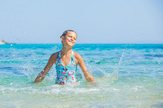 Young girl playing in the wave with spray