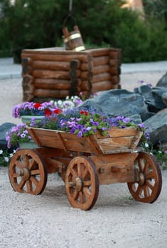 Decorative wooden cart with flowers in the sand against the well