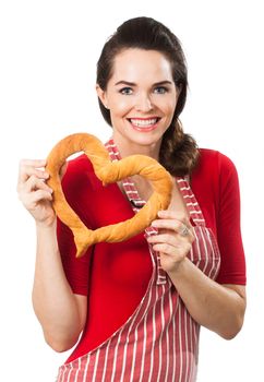 Portrait of  beautiful happy woman wearing an apron and holding  a love heart made out of bread. Isolated on white.
