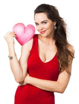 A beautiful seductive young woman in a red dress holding a red love heart. Isolated on white.