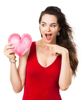 A beautiful excited surporised woman holding and pointing ata love heart. Isolated on white.