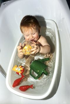 baby in the bath tube with his toys