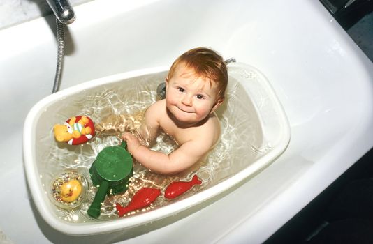 baby playing in bath with plastic toys