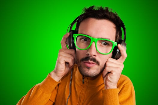 guy with headphones listening to music on green background