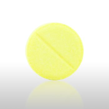 close-up of single yellow pill with shadow