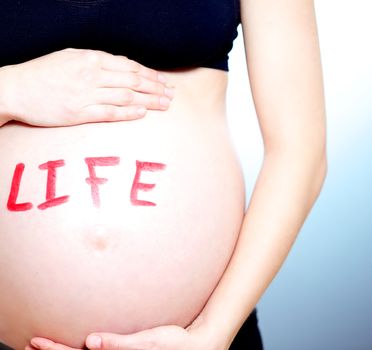 Pregnant woman with the word LIFE on her tummy in red lettering symbolic of her umborn child