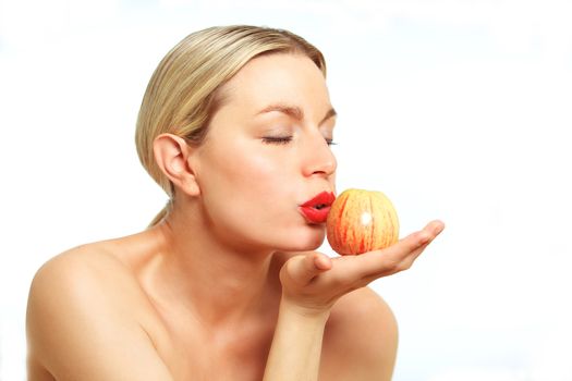 A female model wearing bright red lipstick kissing an Apple.
