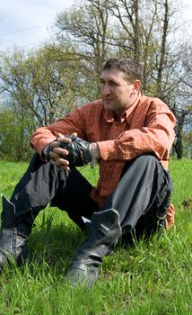 Young man sitting outside on grass in spring landscape