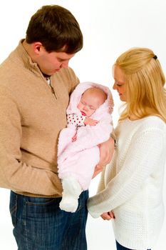 A family portrait of three people in the studio including mother father and newborn baby girl.