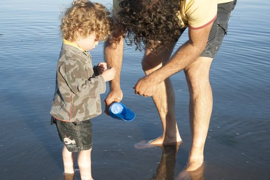 Father and son explore the waters edge, looking at what they have found.