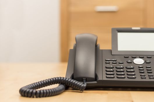 modern black phone on wooden desk with blurred background