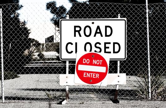 Road Closed Sign Before Chain Link Fence