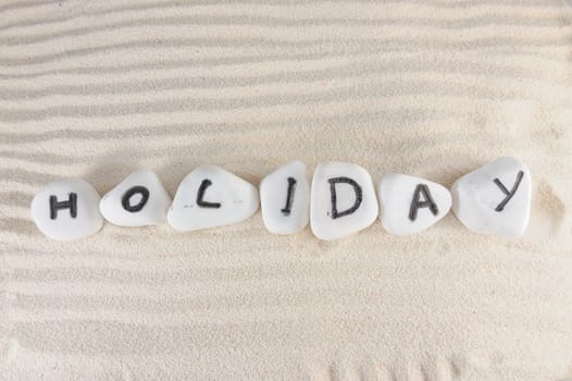 Holiday word on group of stones with sand as background