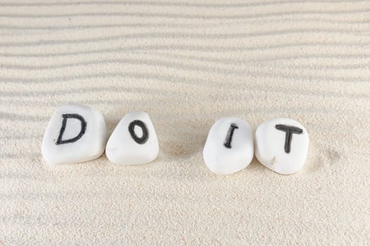Do it words on group of stones with sand as background