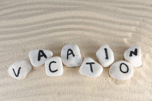 Vacation word on group of stones with sand as background