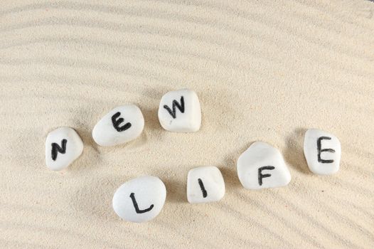 New life word on group of pebbles with sand as background