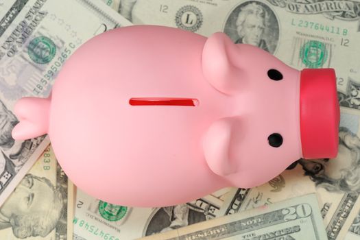Piggy bank on paper money dollar pile