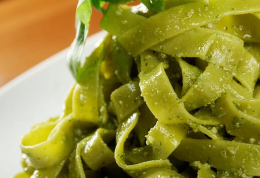 Tagliatelle pasta with pesto on light plate. closeup