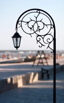 Silhouette wrought park lantern against the beach and sea in summer